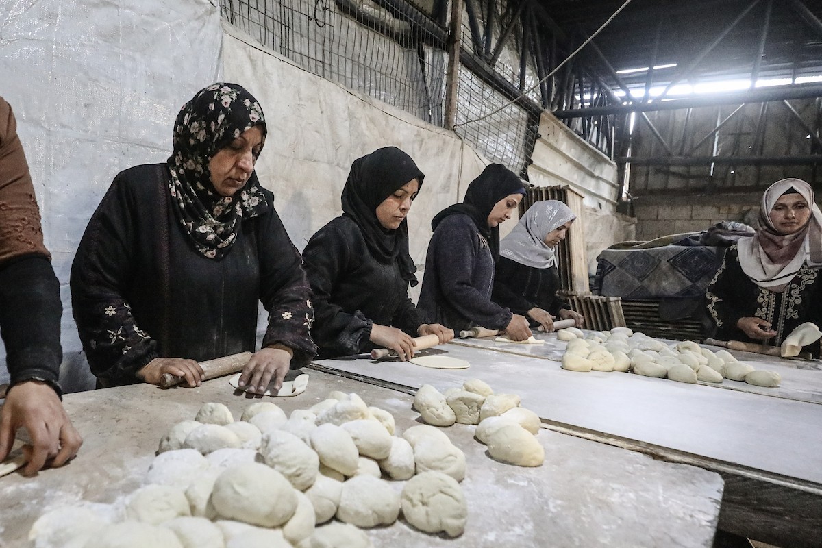 نساء فلسطينيات، زوجات شهداء الحرب، يُجهّزن الخبز لتوزيعه على العائلات النازحة والمحتاجة في مخيم البريج للاجئين وسط قطاع غزة خلال شهر رمضان، في مشهد يُجسّد روح التضامن والصمود في ظلّ الظروف الإنسانية الصعبة، فبراير/شباط 2026. تصوير: معز صالحي