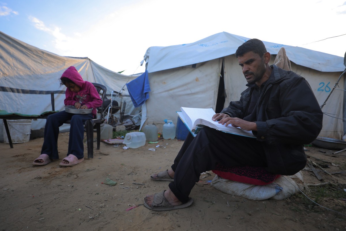 عائلة فلسطينية كفيفة تتناول وجبة الإفطار خارج خيمتها في مخيم بوسط قطاع غزة خلال شهر رمضان