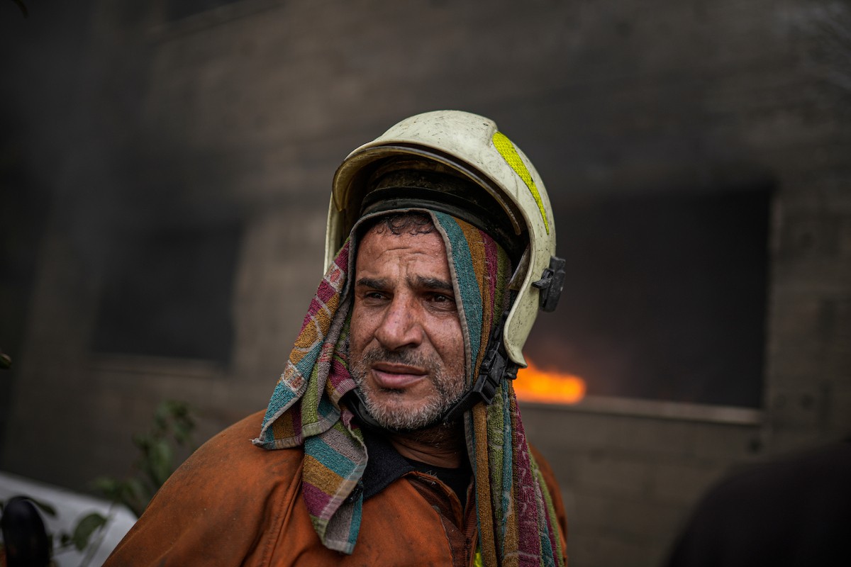 طواقم الدفاع المدني ومتطوعون من المواطنين أثناء محاولة إخماد حريق اندلع في مستودع تابع لمنظمة إغاثة في حي الرمال، غرب مدينة غزة، في 13 فبراير/شباط 2026. صورة: عمر أشتوي