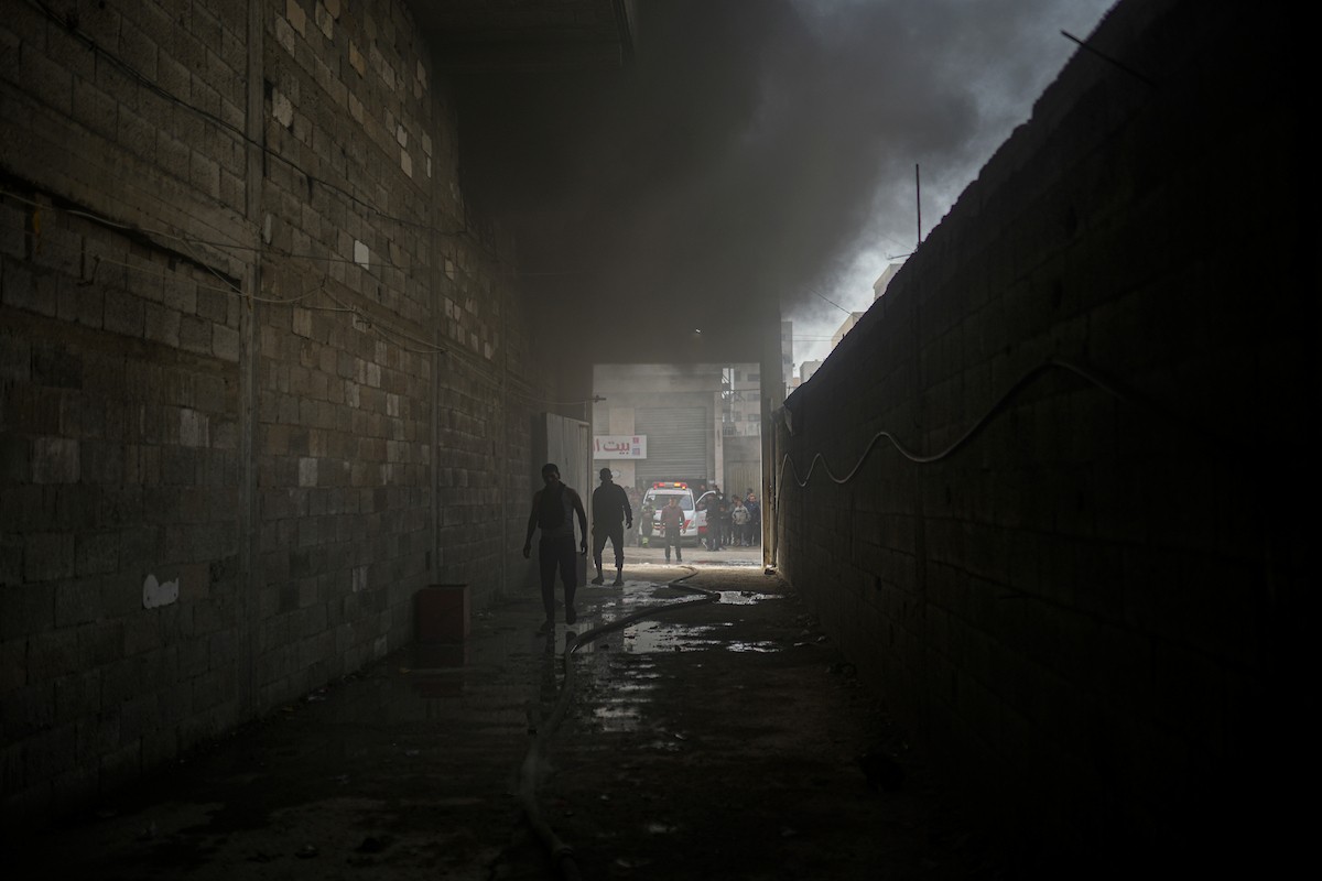 طواقم الدفاع المدني ومتطوعون من المواطنين أثناء محاولة إخماد حريق اندلع في مستودع تابع لمنظمة إغاثة في حي الرمال، غرب مدينة غزة، في 13 فبراير/شباط 2026. صورة: عمر أشتوي