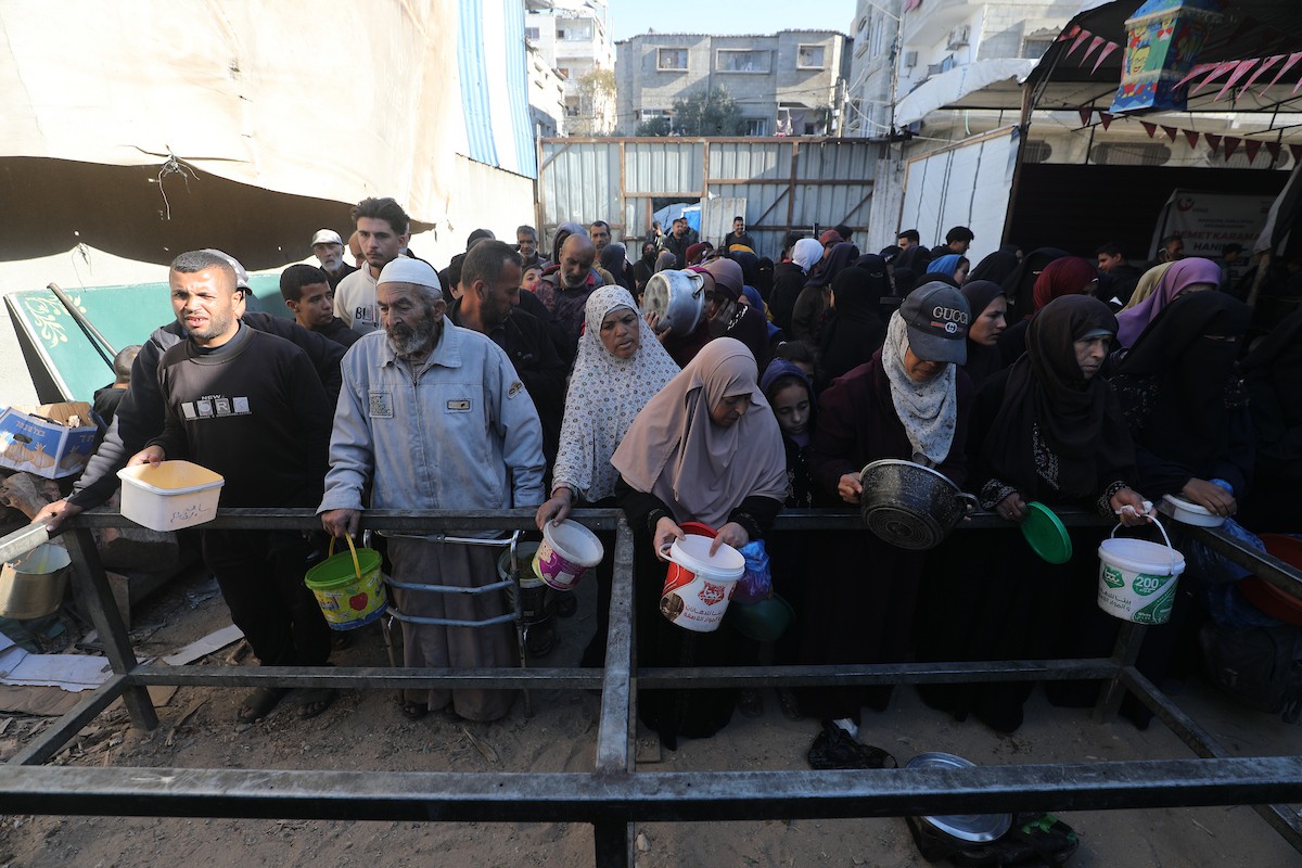 يتجمع فلسطينيون لتناول وجبة ساخنة وزعتها إحدى الجمعيات الخيرية، وسط أزمة غذائية مستمرة بسبب محدودية المساعدات الإنسانية خلال شهر رمضان في مخيم النصيرات للاجئين وسط قطاع غزة. ٢٣ فبرايرشباط ٢٠٢٦. تصوير معز صالحي