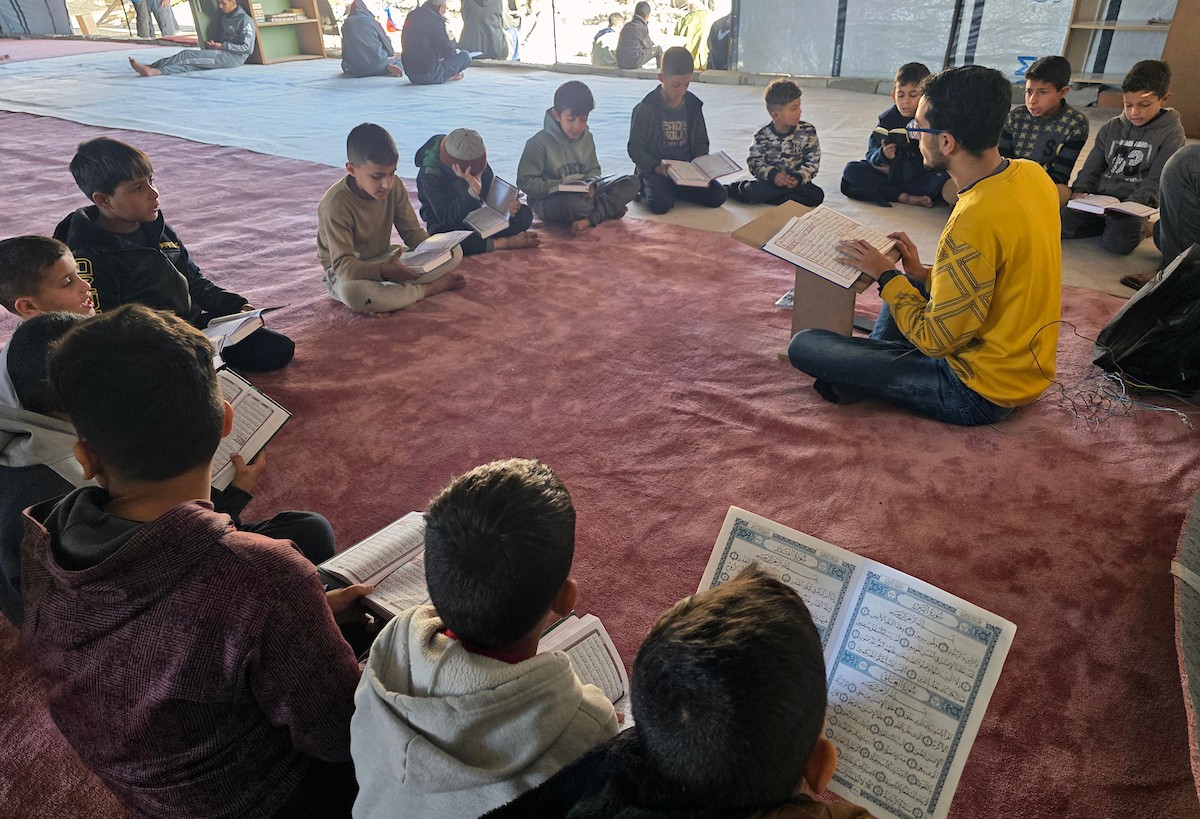 فلسطينيون، بينهم أطفال، يتلون ويحفظون القرآن الكريم خلال شهر رمضان داخل مسجد الألباني، الذي تضرر بشدة جراء الهجمات الإسرائيلية، في خان يونس، جنوب قطاع غزة، في 23 فبراير/شباط 2026. صورة: طارق محمد