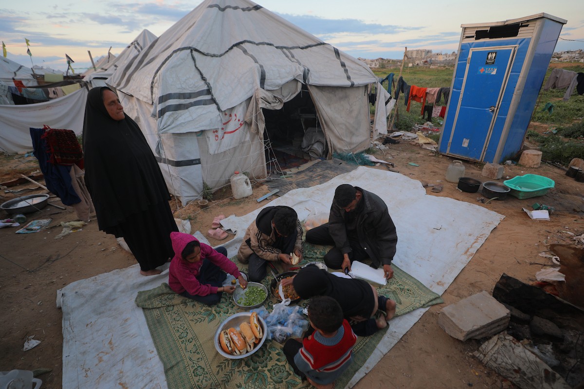 عائلة فلسطينية كفيفة تتناول وجبة الإفطار خارج خيمتها في مخيم بوسط قطاع غزة خلال شهر رمضان