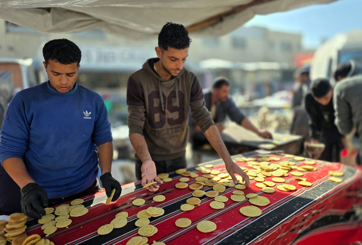 بائعٌ يُعدّ حلوى القطايف الشهيرة بالطرق التقليدية احتفالاً بشهر رمضان المبارك. ورغم الظروف المعيشية الصعبة، يواصل السكان شراء هذه الحلوى التقليدية. خان يونس، جنوب قطاع غزة، ٢٢ فبراير ٢٠٢٦. تصوير: طارق محمد