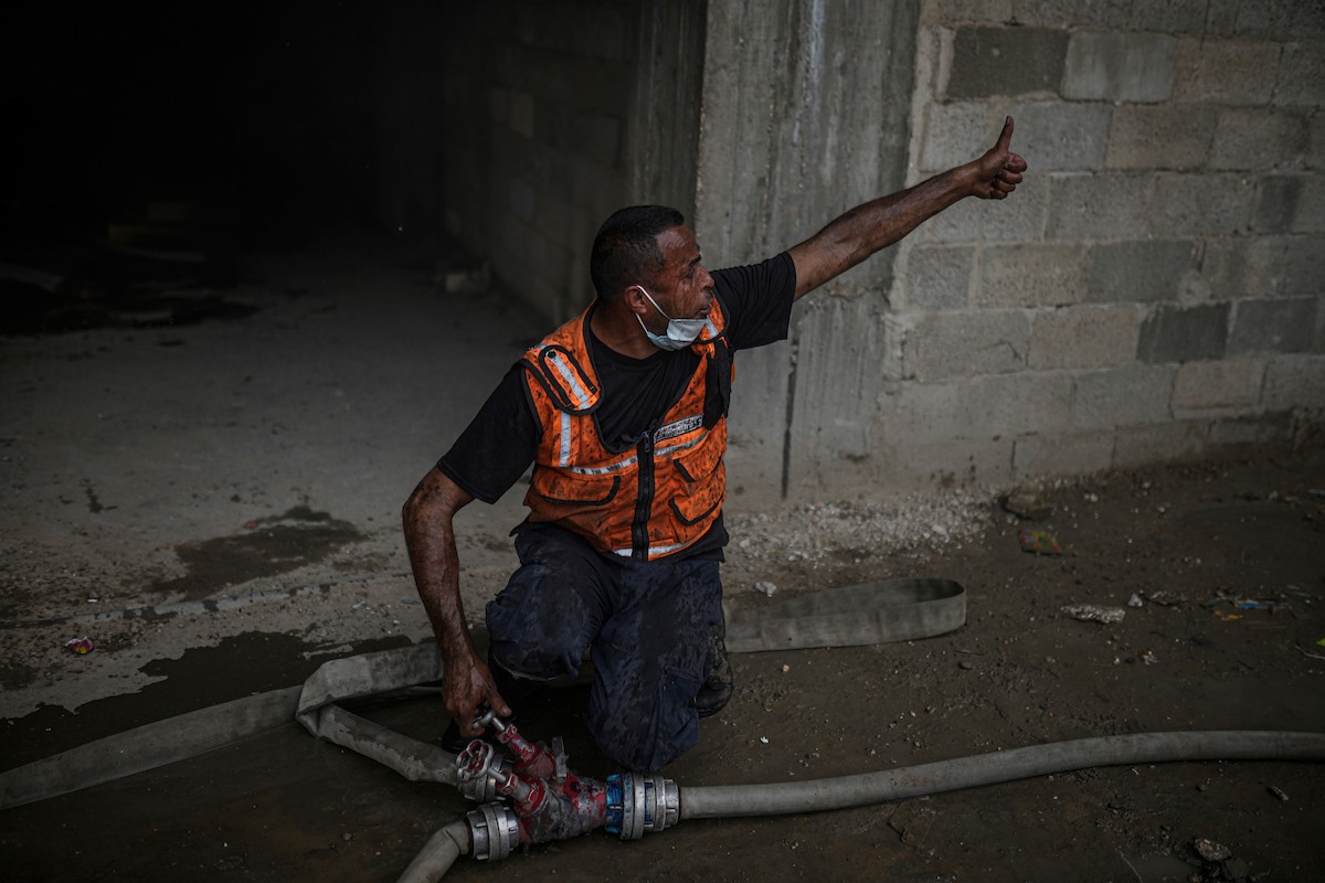 طواقم الدفاع المدني ومتطوعون من المواطنين أثناء محاولة إخماد حريق اندلع في مستودع تابع لمنظمة إغاثة في حي الرمال، غرب مدينة غزة، في 13 فبراير/شباط 2026. صورة: عمر أشتوي