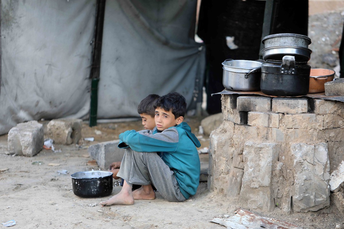 تجمع فلسطينيون نازحون، بينهم أطفال ونساء، حاملين أوعية طعام لتلقي وجبات ساخنة وزعتها جمعيات خيرية قبل الإفطار في مدينة غزة في 27 فبراير/شباط 2026.صورة: عمر أشتوي