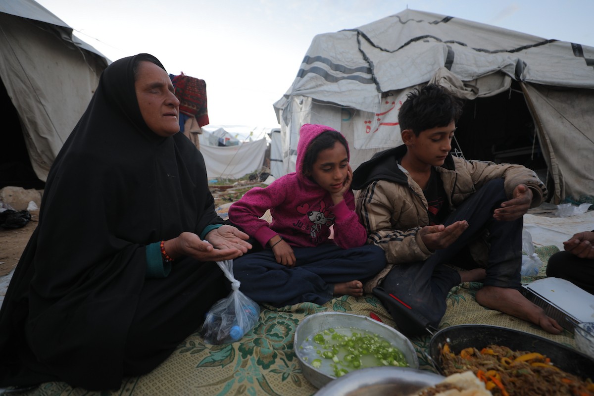 عائلة فلسطينية كفيفة تتناول وجبة الإفطار خارج خيمتها في مخيم بوسط قطاع غزة خلال شهر رمضان