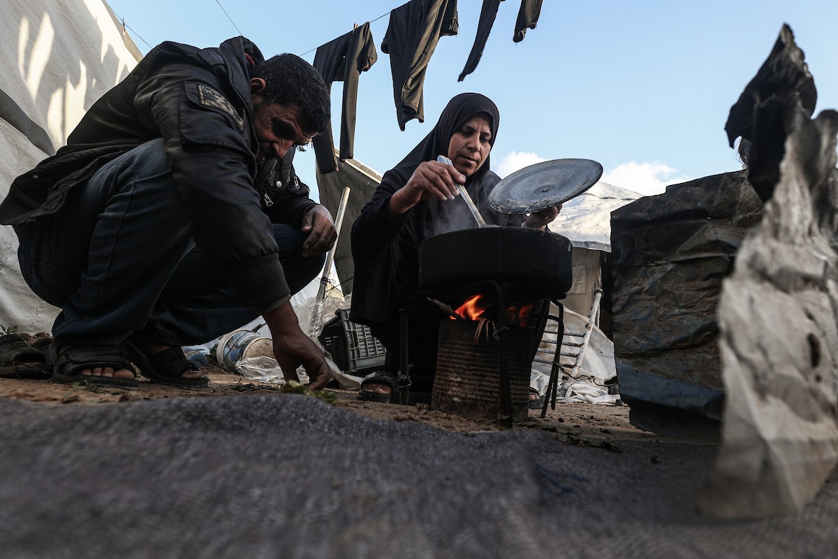 عائلة فلسطينية نازحة تتناول فطورها خلال شهر رمضان داخل خيمة متداعية في مخيم النصيرات للاجئين وسط قطاع غزة. تواجه العائلات النازحة ظروفًا معيشية قاسية نتيجة الحرب، مع انعدام الدخل ونقص حاد في المساعدات الإنسانية، 26 فبراير/شباط 2026. تصوير: معز صالحي