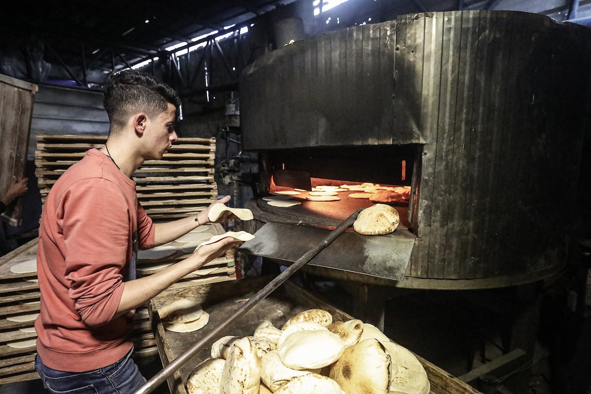 نساء فلسطينيات، زوجات شهداء الحرب، يُجهّزن الخبز لتوزيعه على العائلات النازحة والمحتاجة في مخيم البريج للاجئين وسط قطاع غزة خلال شهر رمضان، في مشهد يُجسّد روح التضامن والصمود في ظلّ الظروف الإنسانية الصعبة، فبراير/شباط 2026. تصوير: معز صالحي