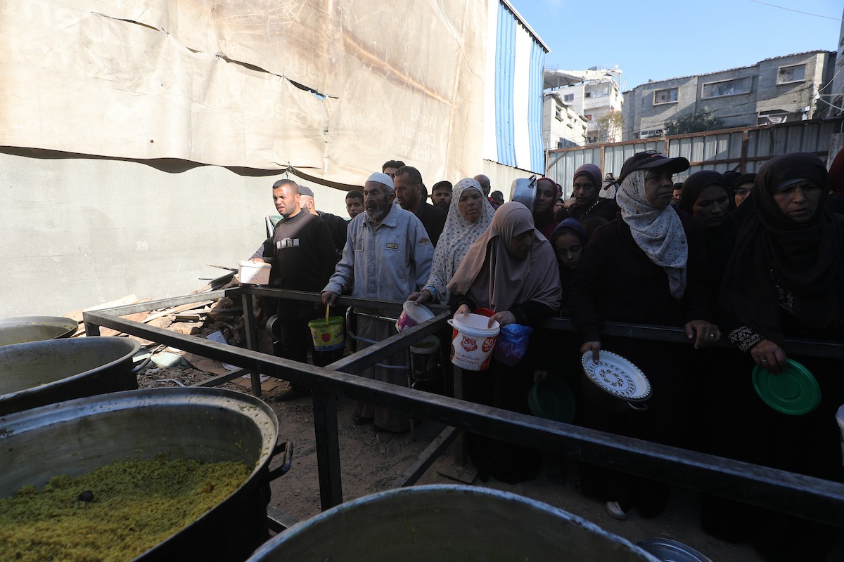 يتجمع فلسطينيون لتناول وجبة ساخنة وزعتها إحدى الجمعيات الخيرية، وسط أزمة غذائية مستمرة بسبب محدودية المساعدات الإنسانية خلال شهر رمضان في مخيم النصيرات للاجئين وسط قطاع غزة. ٢٣ فبرايرشباط ٢٠٢٦. تصوير معز صالحي