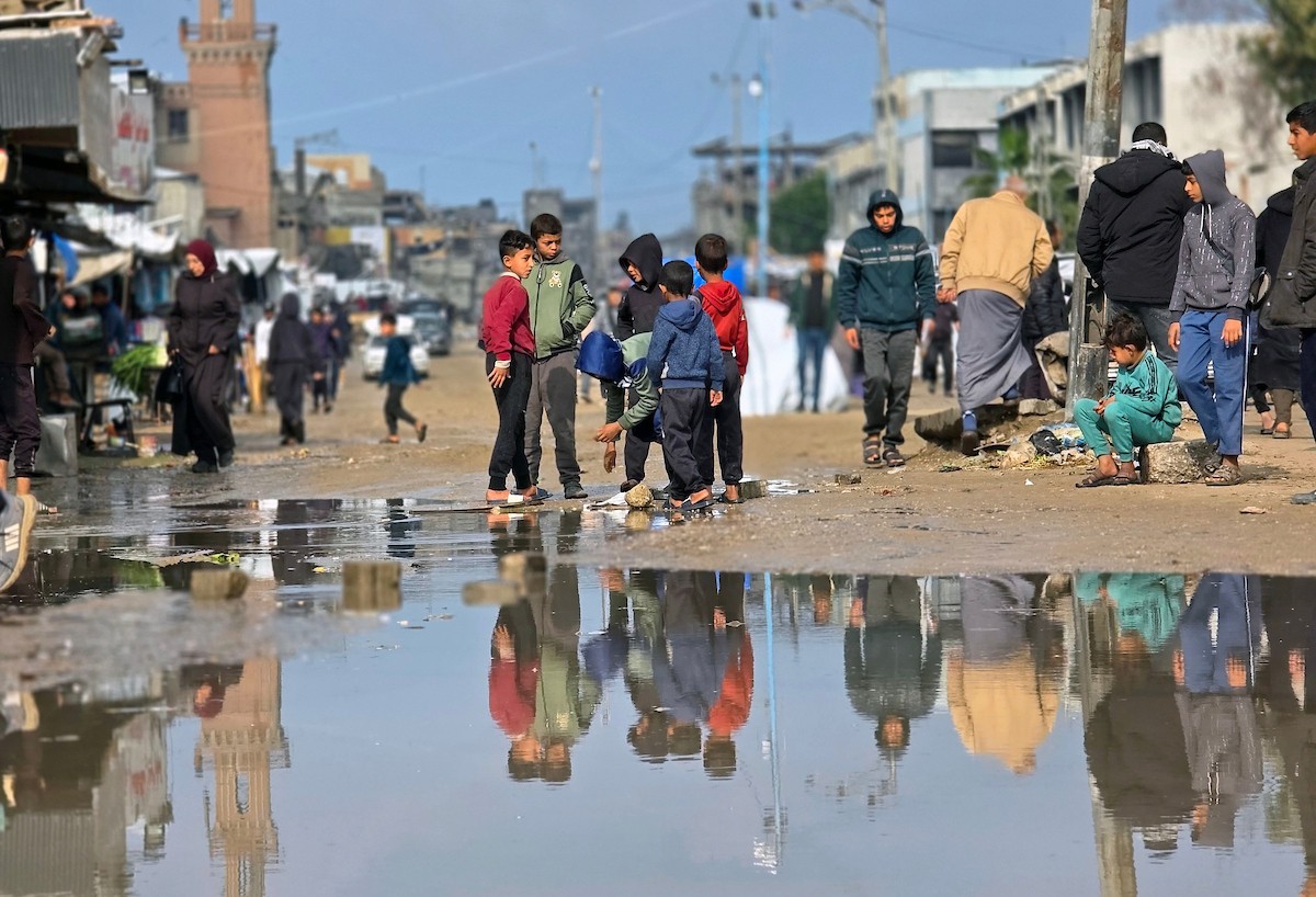 يحاول الفلسطينيون التنقل بعد أن غمرت مياه الأمطار الشوارع وخيام النازحين في خان يونس، جنوب قطاع غزة، في 24 فبراير/شباط 2026. وقد دُمرت البنية التحتية في قطاع غزة على نطاق واسع جراء الحرب والهجمات الإسرائيلية. (صورة: طارق محمد)