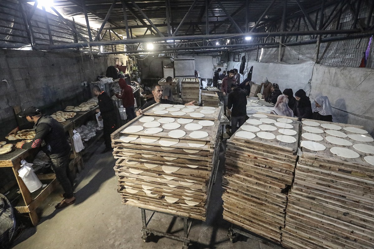 نساء فلسطينيات، زوجات شهداء الحرب، يُجهّزن الخبز لتوزيعه على العائلات النازحة والمحتاجة في مخيم البريج للاجئين وسط قطاع غزة خلال شهر رمضان، في مشهد يُجسّد روح التضامن والصمود في ظلّ الظروف الإنسانية الصعبة، فبراير/شباط 2026. تصوير: معز صالحي