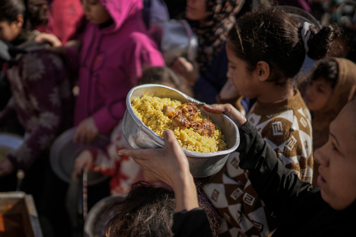 فلسطينيون بينهم أطفال ونساء يتلقون مساعدات غذائية وزعتها منظمات خيرية في أحد مراكز الإيواء بمدينة غزة، وسط أزمة غذائية مستمرة ناجمة عن محدودية المساعدات الإنسانية والظروف الإنسانية المتردية التي يواجهها النازحون، ١٢ فبراير/شباط ٢٠٢٦. تصوير: عمر أشتوي