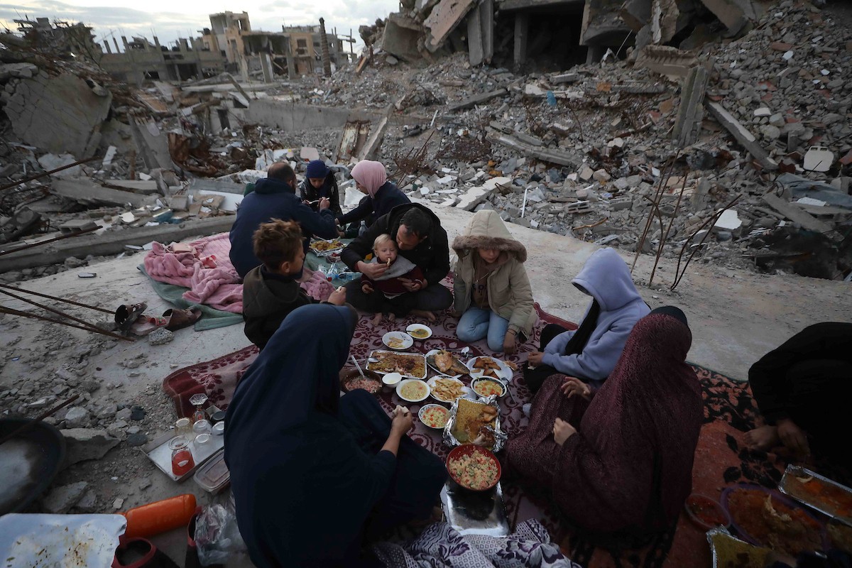 عائلة فلسطينية تتناول إفطارها خلال شهر رمضان على سطح منزلها الذي دمره قصف جوي إسرائيلي خلال حرب غزة في 27 فبراير/شباط 2026. صورة: عمر أشتوي