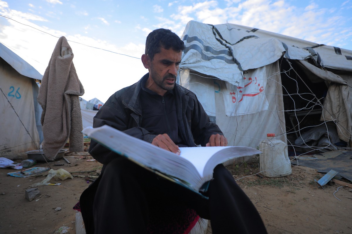 عائلة فلسطينية كفيفة تتناول وجبة الإفطار خارج خيمتها في مخيم بوسط قطاع غزة خلال شهر رمضان