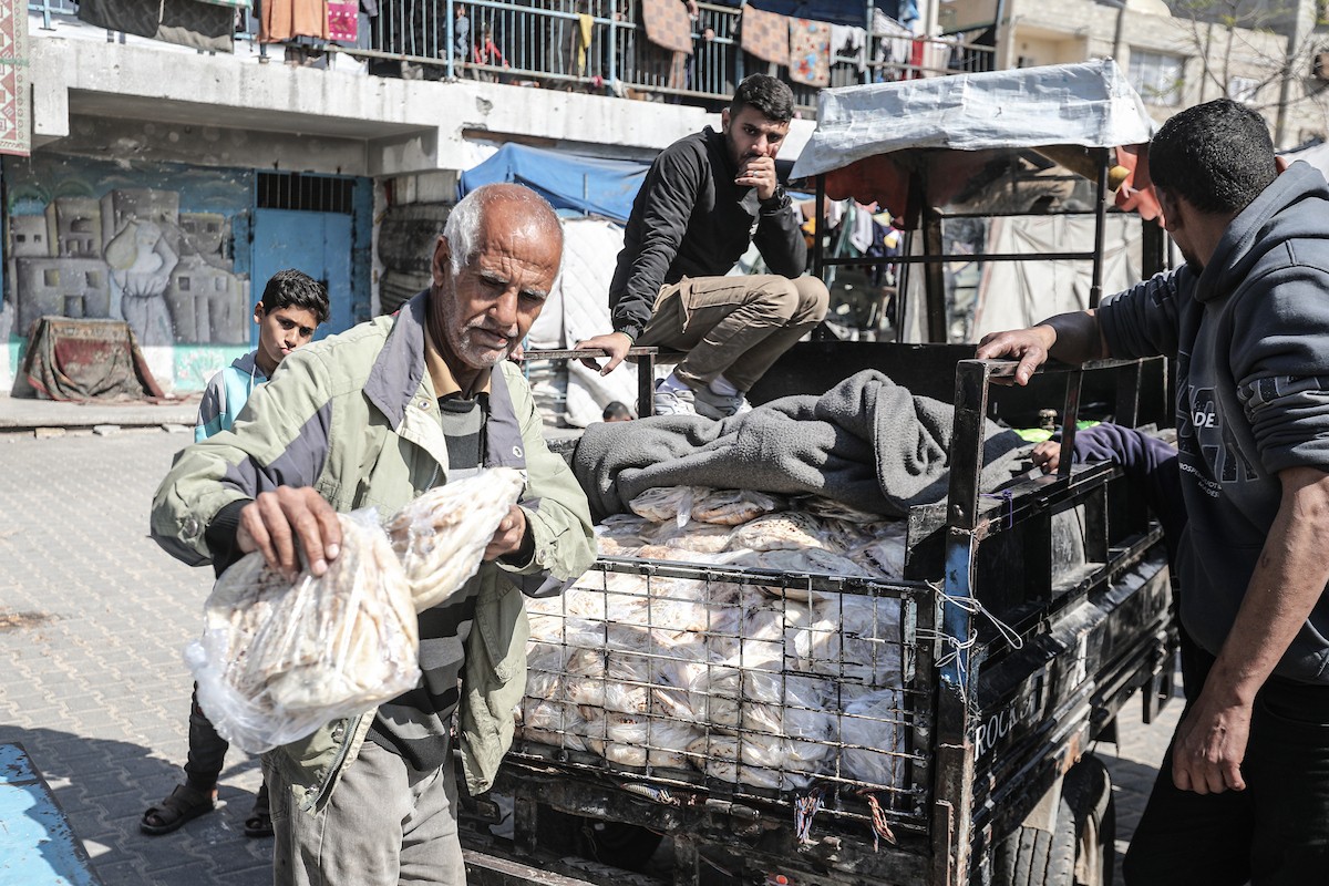 نساء فلسطينيات، زوجات شهداء الحرب، يُجهّزن الخبز لتوزيعه على العائلات النازحة والمحتاجة في مخيم البريج للاجئين وسط قطاع غزة خلال شهر رمضان، في مشهد يُجسّد روح التضامن والصمود في ظلّ الظروف الإنسانية الصعبة، فبراير/شباط 2026. تصوير: معز صالحي
