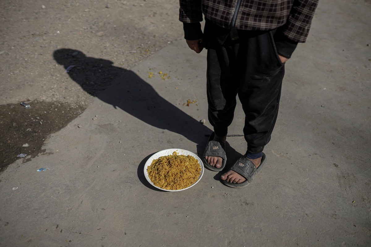 فلسطينيون بينهم أطفال ونساء يتلقون مساعدات غذائية وزعتها منظمات خيرية في أحد مراكز الإيواء بمدينة غزة، وسط أزمة غذائية مستمرة ناجمة عن محدودية المساعدات الإنسانية والظروف الإنسانية المتردية التي يواجهها النازحون، ١٢ فبراير/شباط ٢٠٢٦. تصوير: عمر أشتوي