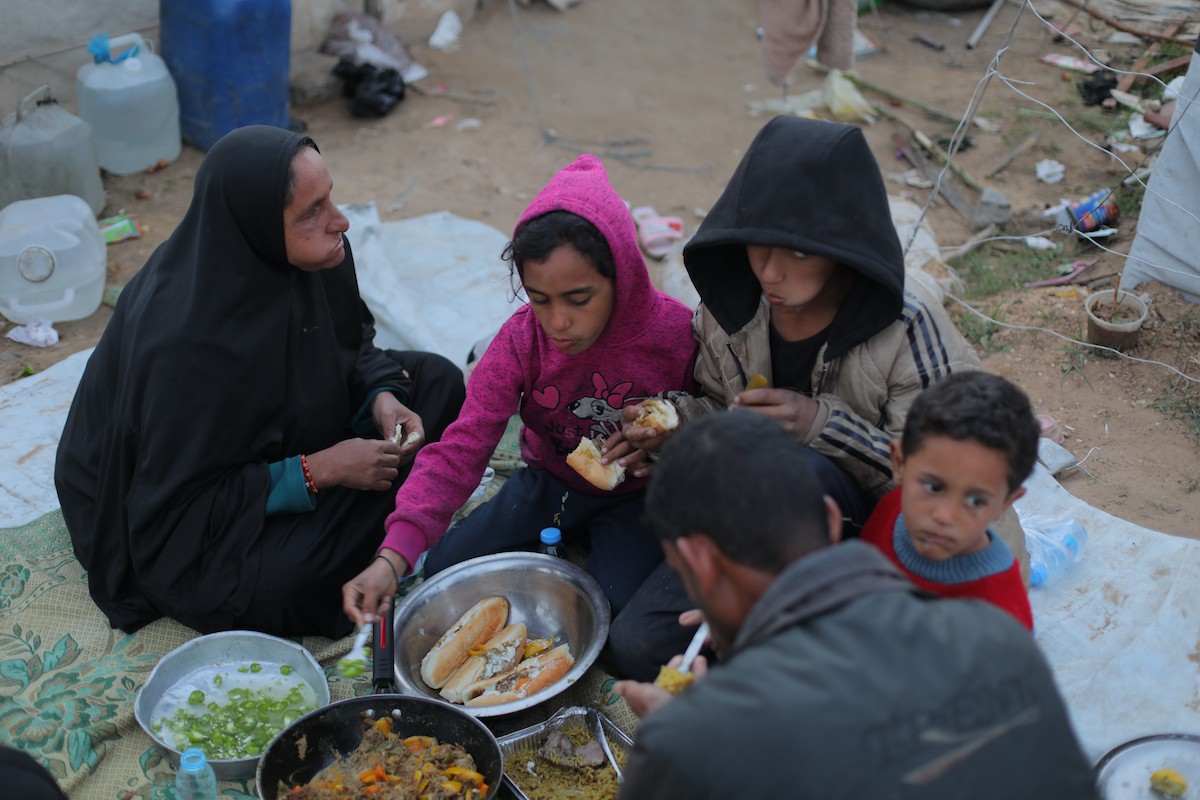 عائلة فلسطينية كفيفة تتناول وجبة الإفطار خارج خيمتها في مخيم بوسط قطاع غزة خلال شهر رمضان