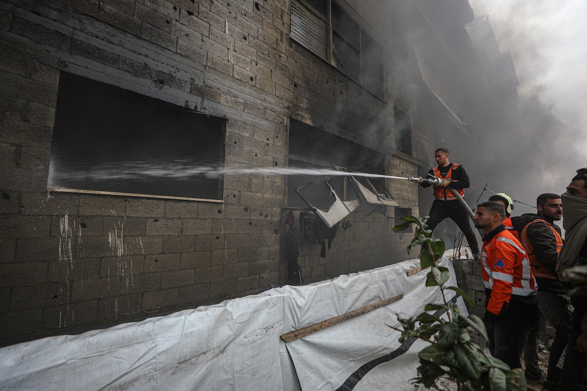 طواقم الدفاع المدني ومتطوعون من المواطنين أثناء محاولة إخماد حريق اندلع في مستودع تابع لمنظمة إغاثة في حي الرمال، غرب مدينة غزة، في 13 فبراير/شباط 2026. صورة: عمر أشتوي