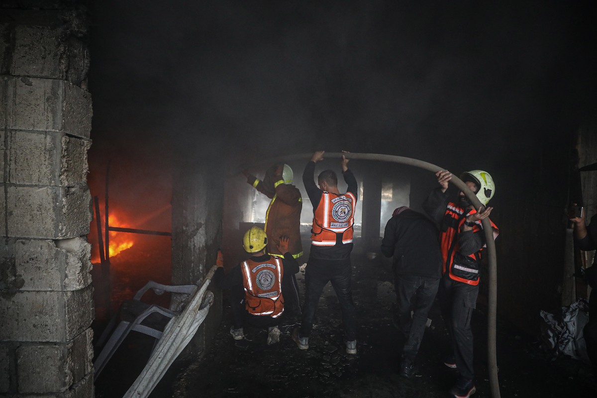 طواقم الدفاع المدني ومتطوعون من المواطنين أثناء محاولة إخماد حريق اندلع في مستودع تابع لمنظمة إغاثة في حي الرمال، غرب مدينة غزة، في 13 فبراير/شباط 2026. صورة: عمر أشتوي