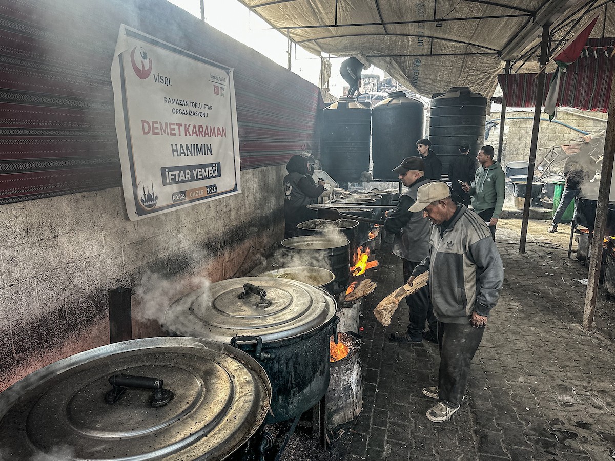 يتجمع فلسطينيون نازحون لتناول وجبة إفطارهم الرمضانية في مطبخ خيري بمخيم النصيرات للاجئين وسط قطاع غزة، في 24 فبراير/شباط 2026. ويواجه النازحون ظروفًا معيشية قاسية نتيجة انعدام الدخل ونقص المساعدات الإنسانية. (صورة: رمزي أبو عامر / apaimages)