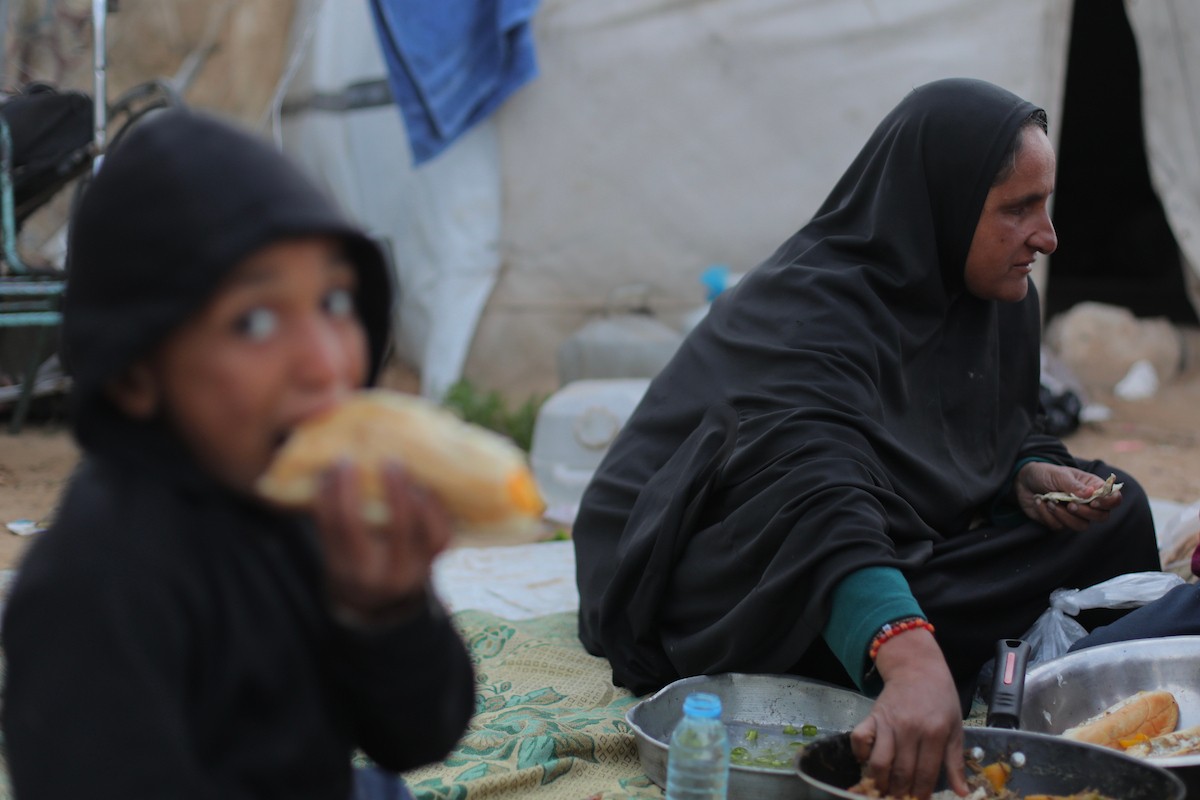 عائلة فلسطينية كفيفة تتناول وجبة الإفطار خارج خيمتها في مخيم بوسط قطاع غزة خلال شهر رمضان