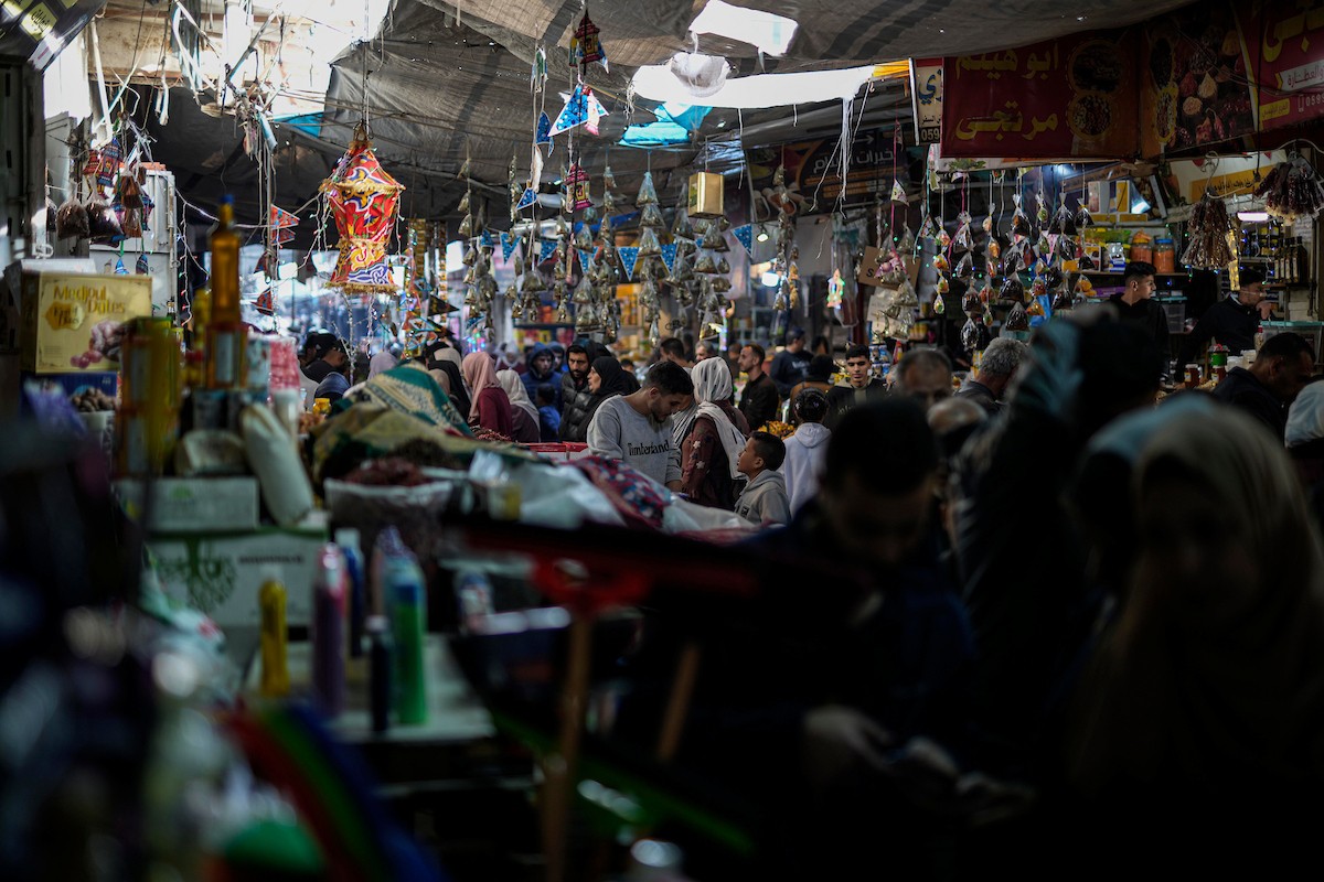 يتسوق الفلسطينيون في أول ليلة من شهر رمضان المبارك في سوق الزاوية، الواقع في قلب مدينة غزة والذي تضرر بشدة جراء الحرب الإسرائيلية. يعرض الباعة بضائعهم على أكشاك مزينة بالفوانيس والأضواء وأطعمة رمضان. مدينة غزة، 17 فبراير/شباط 2026. تصوير: عمر أشتوي