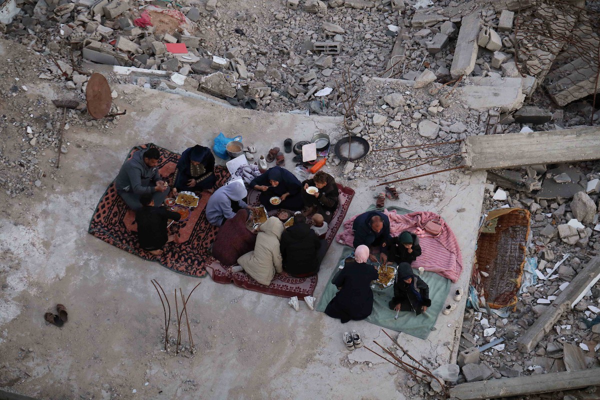 عائلة فلسطينية تتناول إفطارها خلال شهر رمضان على سطح منزلها الذي دمره قصف جوي إسرائيلي خلال حرب غزة في 27 فبراير/شباط 2026. صورة: عمر أشتوي
