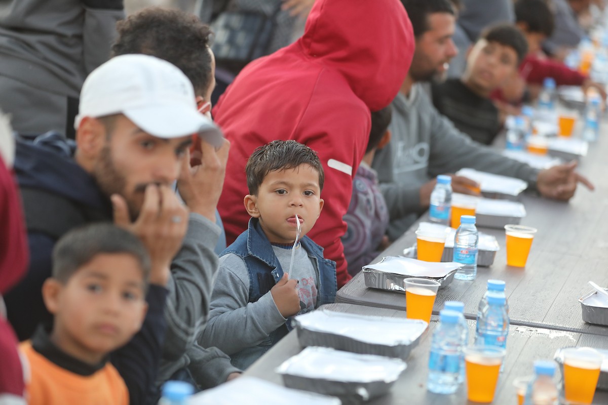 يتجمع فلسطينيون نازحون لتناول وجبة الإفطار وسط أنقاض المباني المدمرة في مدينة غزة، خلال شهر رمضان المبارك، في 25 فبراير/شباط 2026. صورة: عمر أشتوي