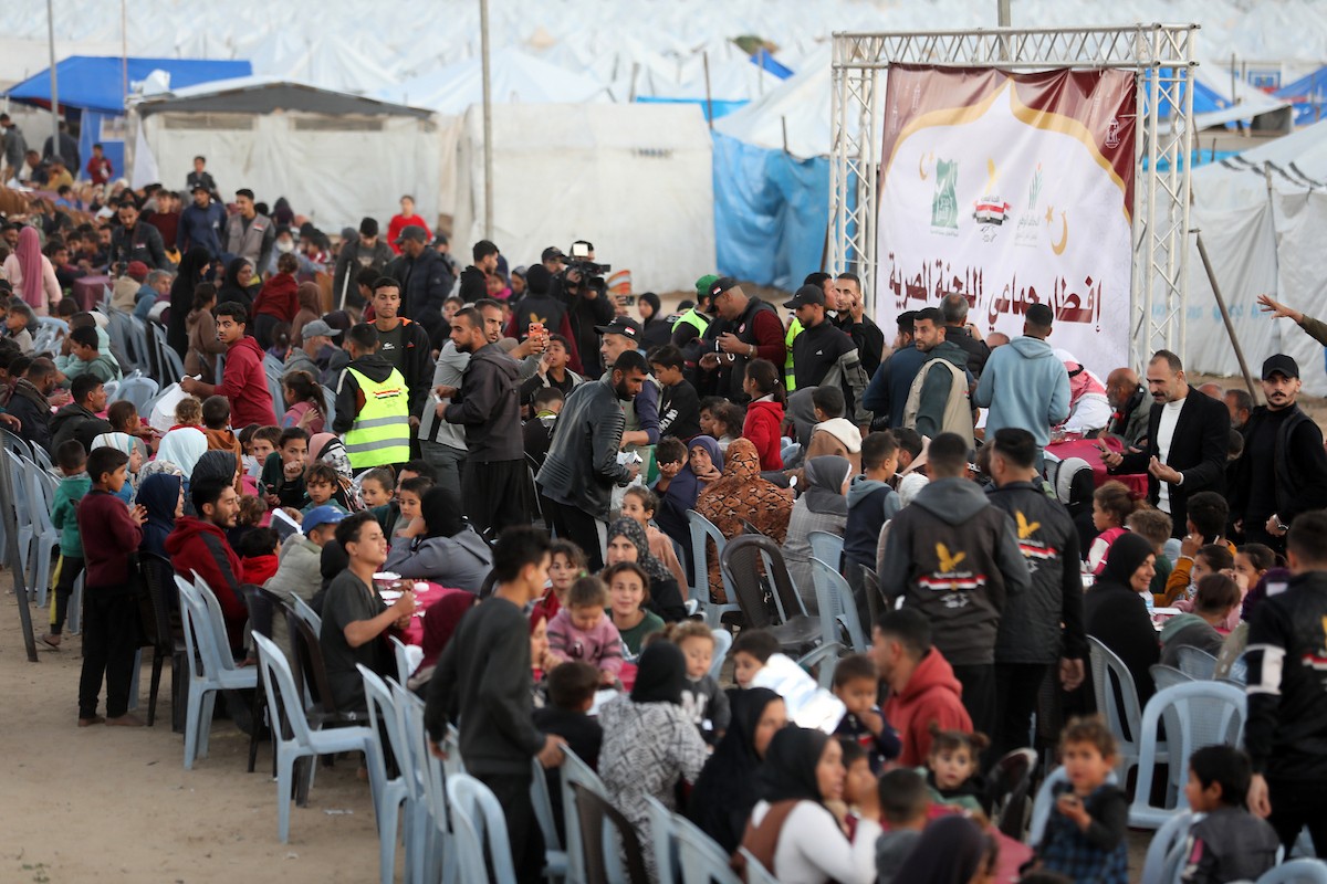 يتجمع فلسطينيون نازحون لتناول وجبة الإفطار، وهي وجبة كسر الصيام، خلال شهر رمضان المبارك في مخيم خيام يؤويهم، بحي الزهراء وسط قطاع غزة، يوم السبت 21 فبراير/شباط 2026. تصوير: عمر أشتوي