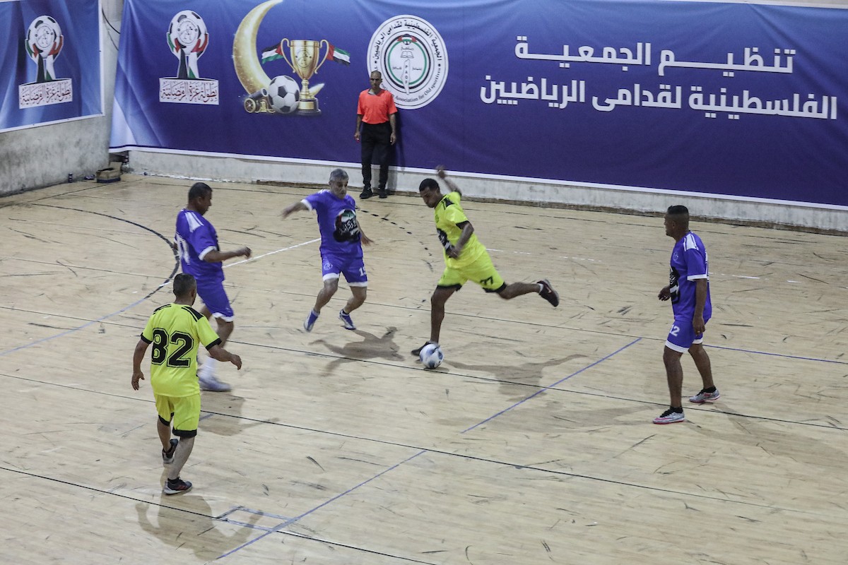 لاعبون فلسطينيون من فريقي النصيرات ورفح يتنافسون خلال مباراة كرة قدم على ملعب نادي خدمات النصيرات، ضمن بطولة غزة الرمضانية، بحضور حشد جماهيري كبير، في مخيم النصيرات بوسط قطاع غزة، بتاريخ 21 فبراير/شباط 2026. تصوير: معز صالحي / apaimages