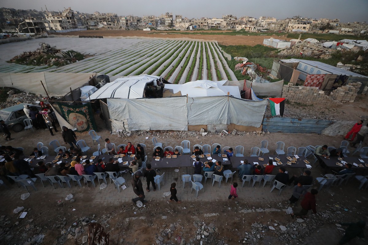 يتجمع فلسطينيون نازحون لتناول وجبة الإفطار وسط أنقاض المباني المدمرة في مدينة غزة، خلال شهر رمضان المبارك، في 25 فبراير/شباط 2026. صورة: عمر أشتوي