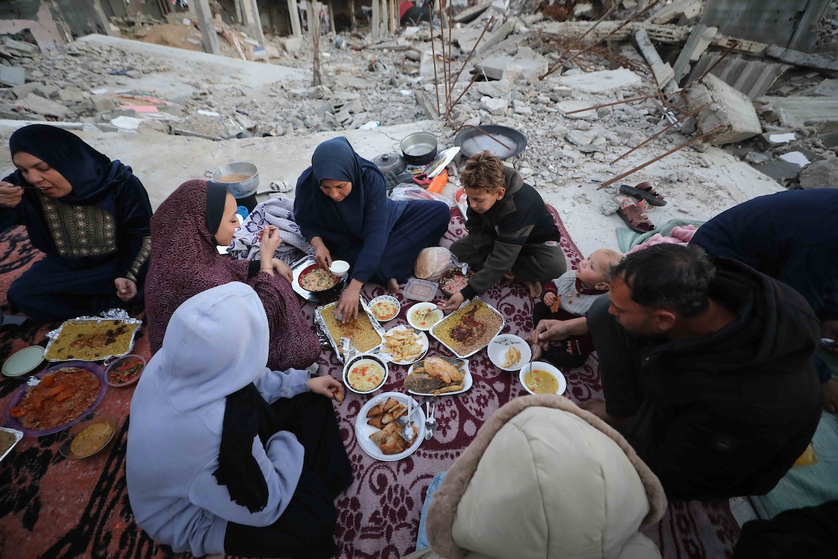 عائلة فلسطينية تتناول إفطارها خلال شهر رمضان على سطح منزلها الذي دمره قصف جوي إسرائيلي خلال حرب غزة في 27 فبراير/شباط 2026. صورة: عمر أشتوي