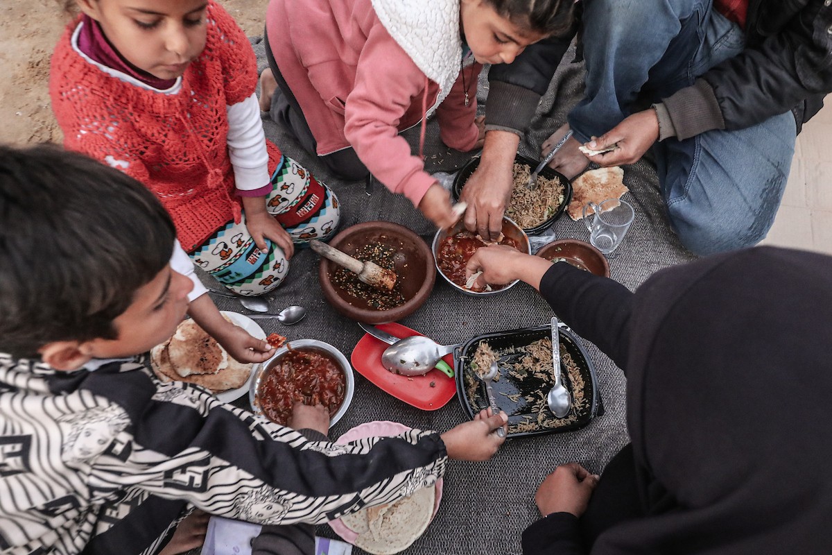 عائلة فلسطينية نازحة تتناول فطورها خلال شهر رمضان داخل خيمة متداعية في مخيم النصيرات للاجئين وسط قطاع غزة. تواجه العائلات النازحة ظروفًا معيشية قاسية نتيجة الحرب، مع انعدام الدخل ونقص حاد في المساعدات الإنسانية، 26 فبراير/شباط 2026. تصوير: معز صالحي
