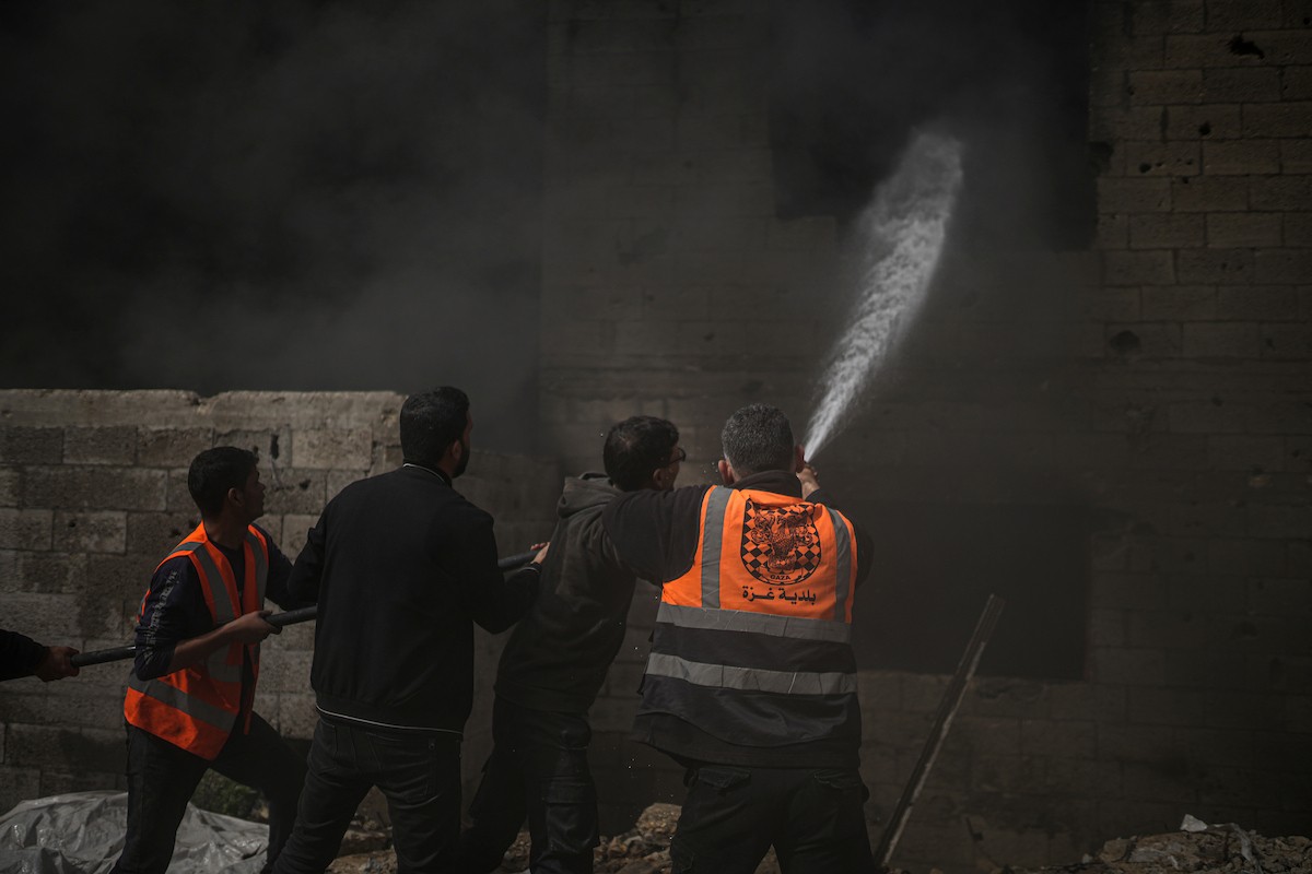 طواقم الدفاع المدني ومتطوعون من المواطنين أثناء محاولة إخماد حريق اندلع في مستودع تابع لمنظمة إغاثة في حي الرمال، غرب مدينة غزة، في 13 فبراير/شباط 2026. صورة: عمر أشتوي