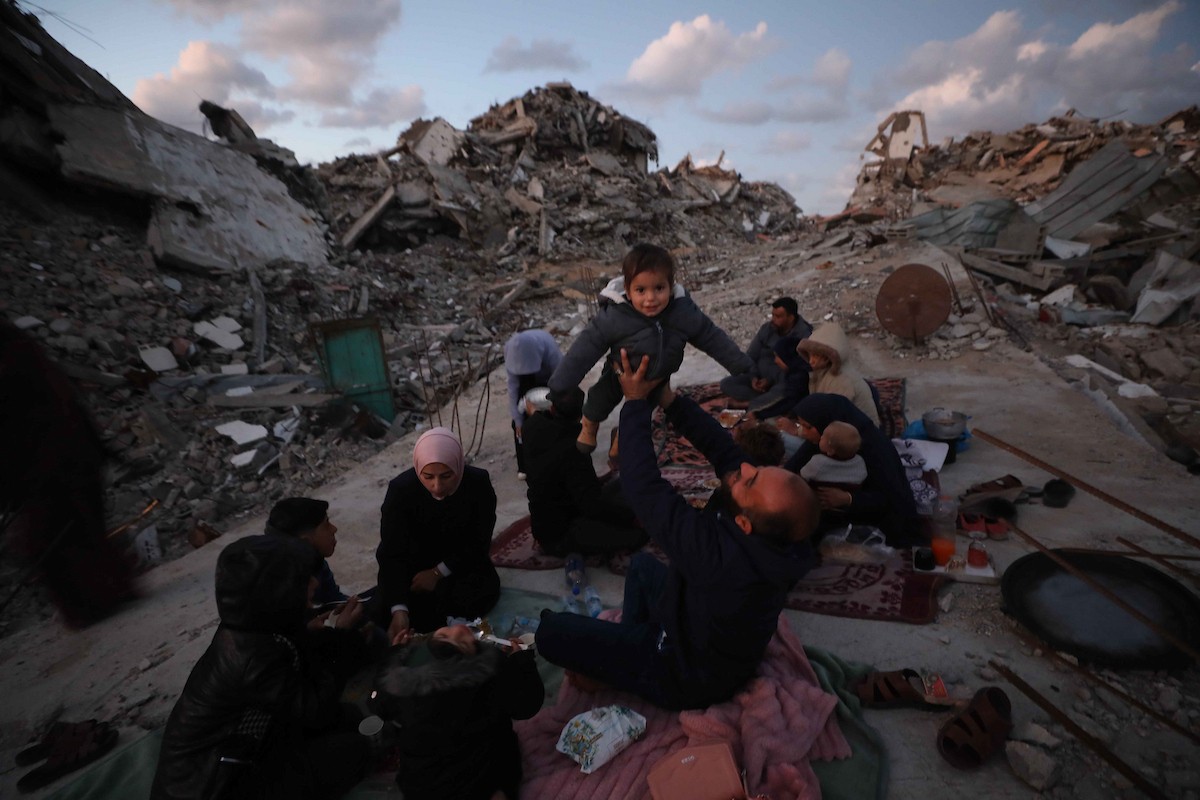 عائلة فلسطينية تتناول إفطارها خلال شهر رمضان على سطح منزلها الذي دمره قصف جوي إسرائيلي خلال حرب غزة في 27 فبراير/شباط 2026. صورة: عمر أشتوي