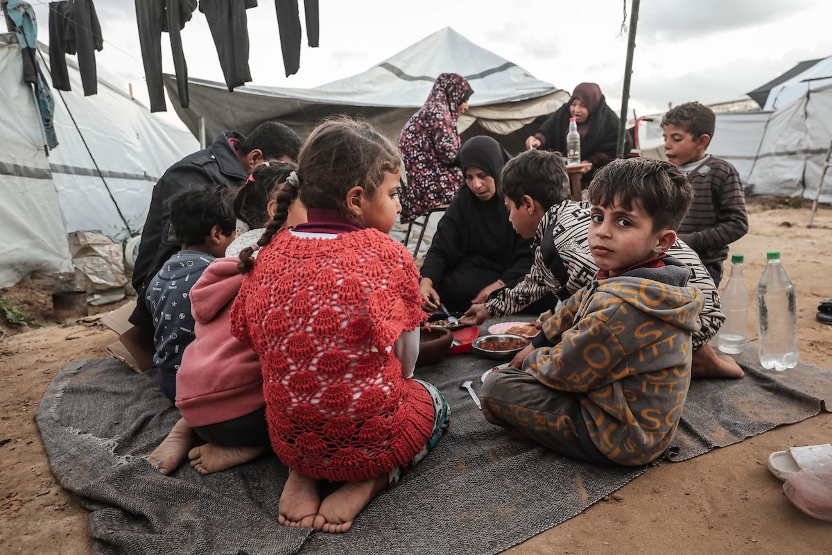 عائلة فلسطينية نازحة تتناول فطورها خلال شهر رمضان داخل خيمة متداعية في مخيم النصيرات للاجئين وسط قطاع غزة. تواجه العائلات النازحة ظروفًا معيشية قاسية نتيجة الحرب، مع انعدام الدخل ونقص حاد في المساعدات الإنسانية، 26 فبراير/شباط 2026. تصوير: معز صالحي