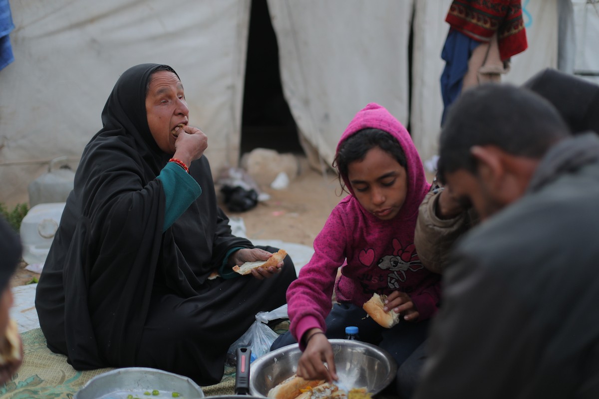 عائلة فلسطينية كفيفة تتناول وجبة الإفطار خارج خيمتها في مخيم بوسط قطاع غزة خلال شهر رمضان