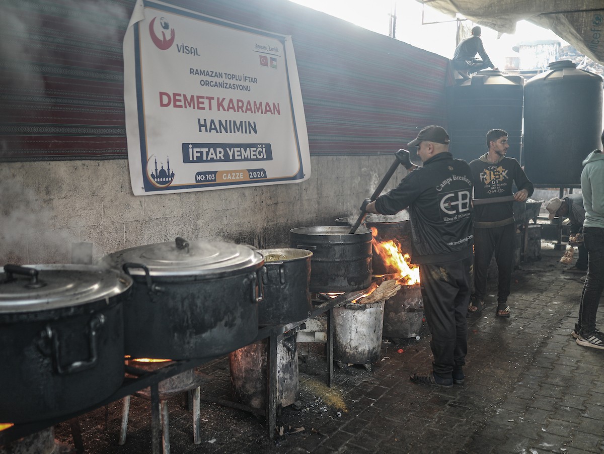 يتجمع فلسطينيون نازحون لتناول وجبة إفطارهم الرمضانية في مطبخ خيري بمخيم النصيرات للاجئين وسط قطاع غزة، في 24 فبراير/شباط 2026. ويواجه النازحون ظروفًا معيشية قاسية نتيجة انعدام الدخل ونقص المساعدات الإنسانية. (صورة: رمزي أبو عامر / apaimages)