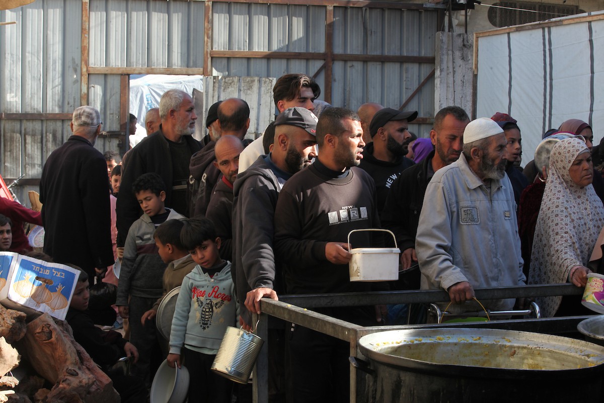 يتجمع فلسطينيون لتناول وجبة ساخنة وزعتها إحدى الجمعيات الخيرية، وسط أزمة غذائية مستمرة بسبب محدودية المساعدات الإنسانية خلال شهر رمضان في مخيم النصيرات للاجئين وسط قطاع غزة. ٢٣ فبرايرشباط ٢٠٢٦. تصوير معز صالحي