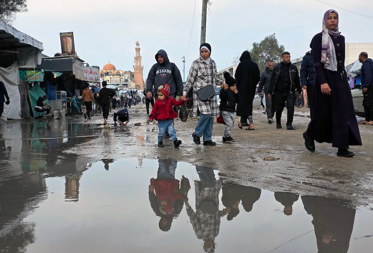 يحاول الفلسطينيون التنقل بعد أن غمرت مياه الأمطار الشوارع وخيام النازحين في خان يونس، جنوب قطاع غزة، في 24 فبراير/شباط 2026. وقد دُمرت البنية التحتية في قطاع غزة على نطاق واسع جراء الحرب والهجمات الإسرائيلية. (صورة: طارق محمد)