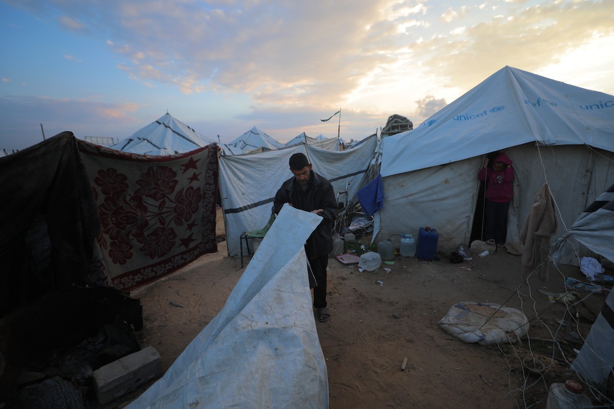 عائلة فلسطينية كفيفة تتناول وجبة الإفطار خارج خيمتها في مخيم بوسط قطاع غزة خلال شهر رمضان