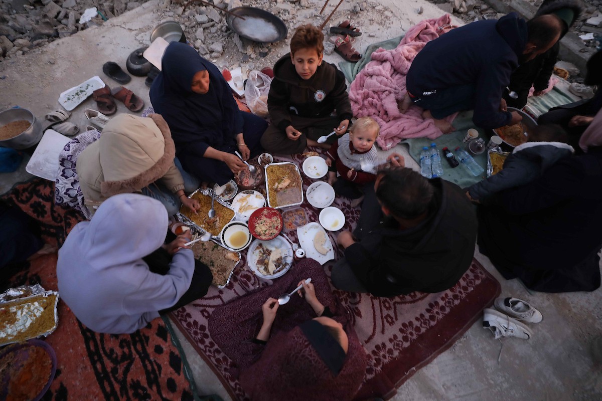 عائلة فلسطينية تتناول إفطارها خلال شهر رمضان على سطح منزلها الذي دمره قصف جوي إسرائيلي خلال حرب غزة في 27 فبراير/شباط 2026. صورة: عمر أشتوي