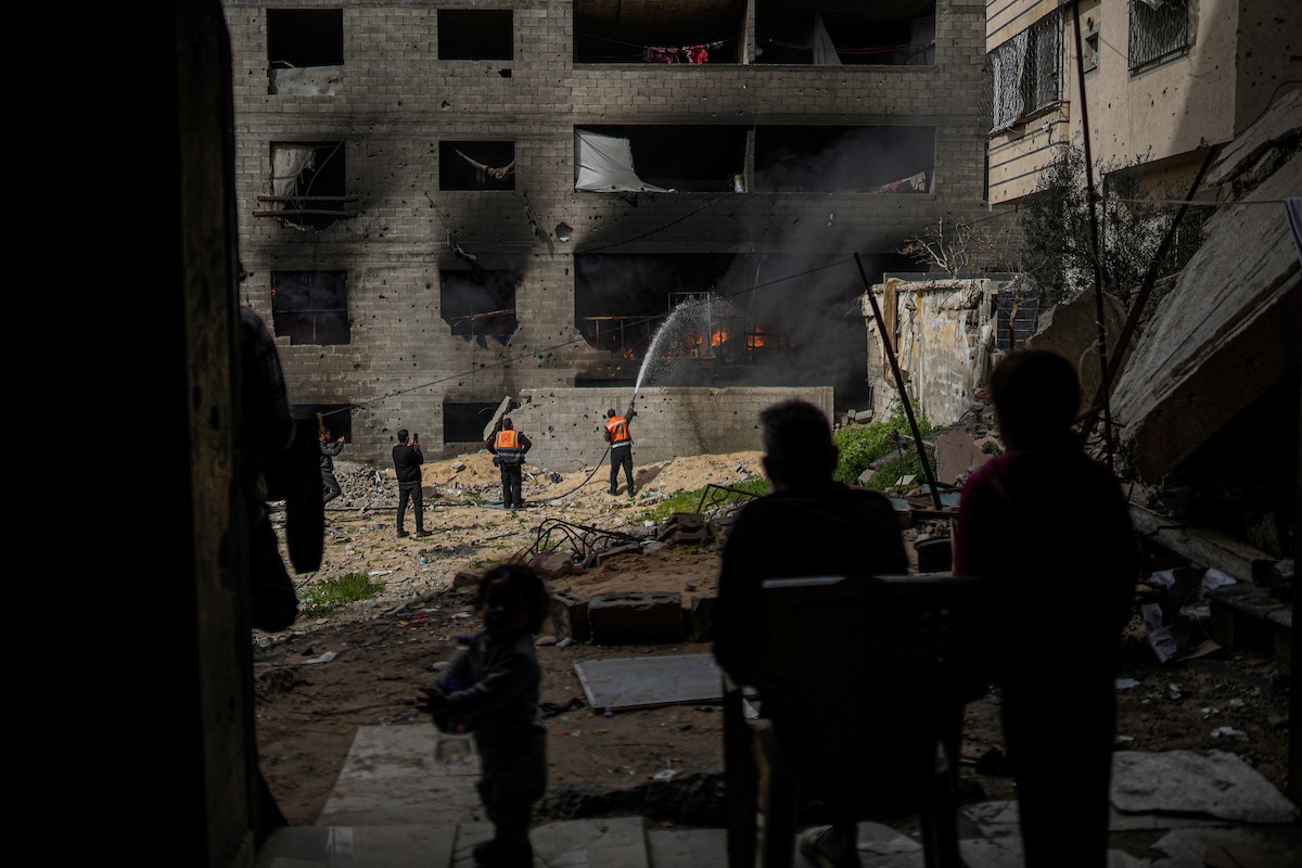 طواقم الدفاع المدني ومتطوعون من المواطنين أثناء محاولة إخماد حريق اندلع في مستودع تابع لمنظمة إغاثة في حي الرمال، غرب مدينة غزة، في 13 فبراير/شباط 2026. صورة: عمر أشتوي