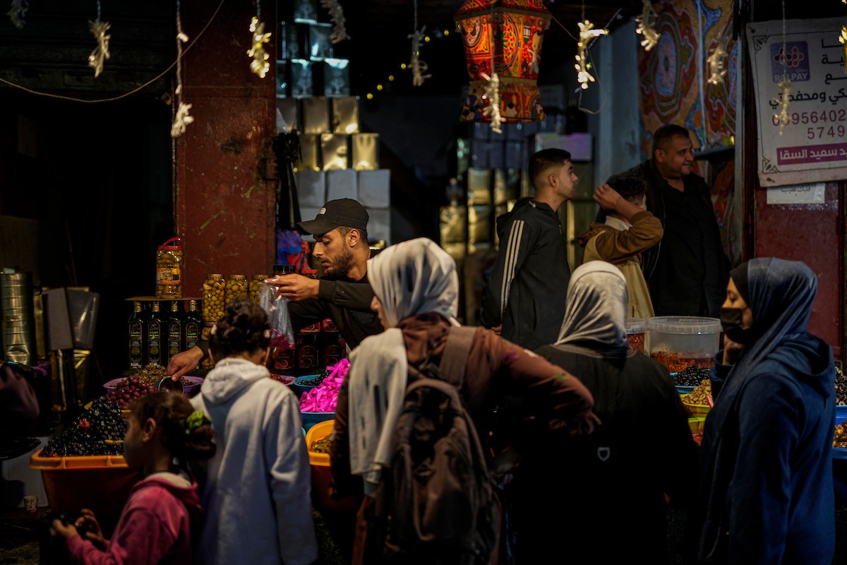 يتسوق الفلسطينيون في أول ليلة من شهر رمضان المبارك في سوق الزاوية، الواقع في قلب مدينة غزة والذي تضرر بشدة جراء الحرب الإسرائيلية. يعرض الباعة بضائعهم على أكشاك مزينة بالفوانيس والأضواء وأطعمة رمضان. مدينة غزة، 17 فبراير/شباط 2026. تصوير: عمر أشتوي