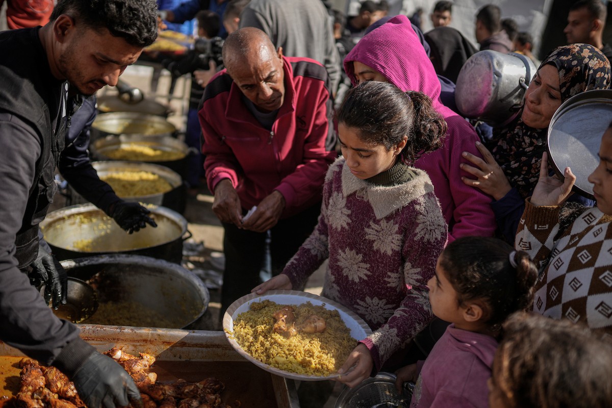 فلسطينيون بينهم أطفال ونساء يتلقون مساعدات غذائية وزعتها منظمات خيرية في أحد مراكز الإيواء بمدينة غزة، وسط أزمة غذائية مستمرة ناجمة عن محدودية المساعدات الإنسانية والظروف الإنسانية المتردية التي يواجهها النازحون، ١٢ فبراير/شباط ٢٠٢٦. تصوير: عمر أشتوي