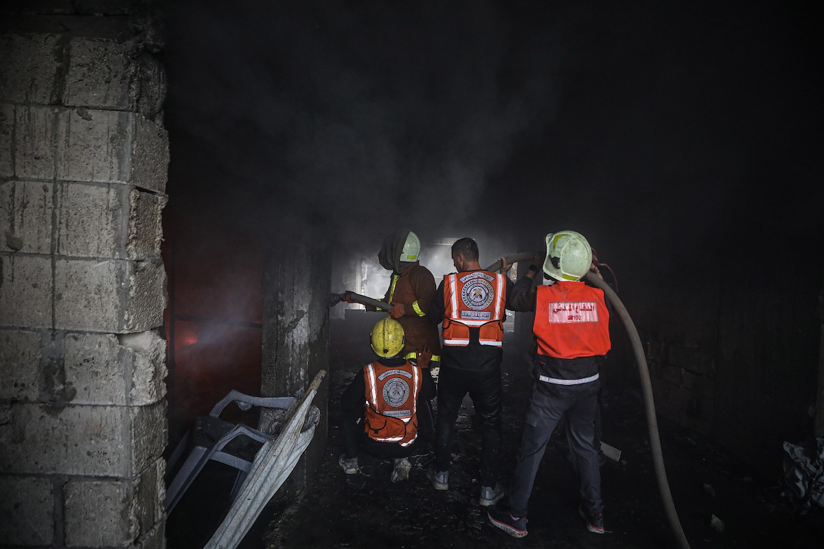 طواقم الدفاع المدني ومتطوعون من المواطنين أثناء محاولة إخماد حريق اندلع في مستودع تابع لمنظمة إغاثة في حي الرمال، غرب مدينة غزة، في 13 فبراير/شباط 2026. صورة: عمر أشتوي