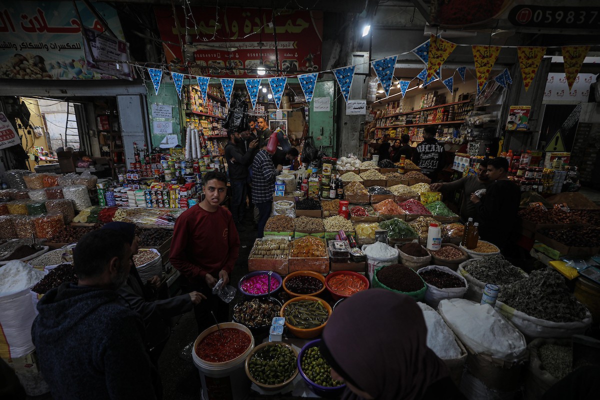 يتسوق الفلسطينيون في أول ليلة من شهر رمضان المبارك في سوق الزاوية، الواقع في قلب مدينة غزة والذي تضرر بشدة جراء الحرب الإسرائيلية. يعرض الباعة بضائعهم على أكشاك مزينة بالفوانيس والأضواء وأطعمة رمضان. مدينة غزة، 17 فبراير/شباط 2026. تصوير: عمر أشتوي