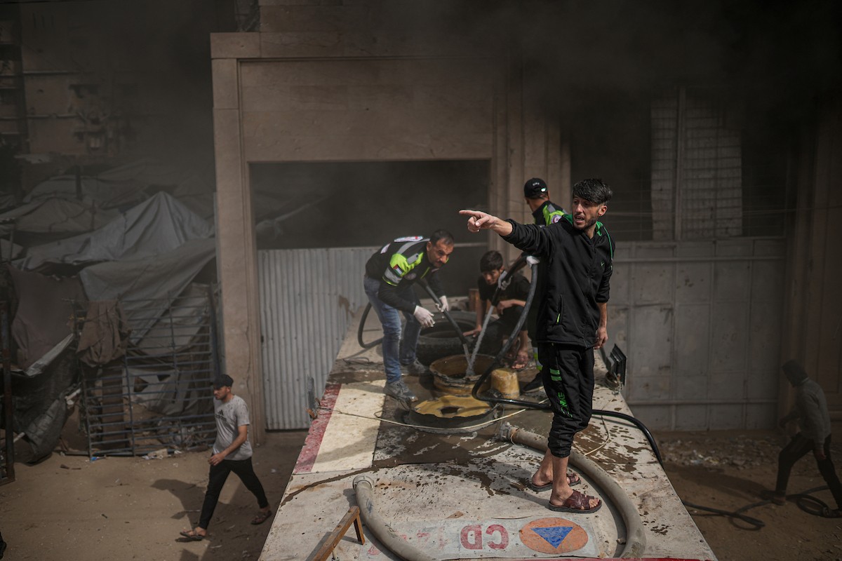 طواقم الدفاع المدني ومتطوعون من المواطنين أثناء محاولة إخماد حريق اندلع في مستودع تابع لمنظمة إغاثة في حي الرمال، غرب مدينة غزة، في 13 فبراير/شباط 2026. صورة: عمر أشتوي