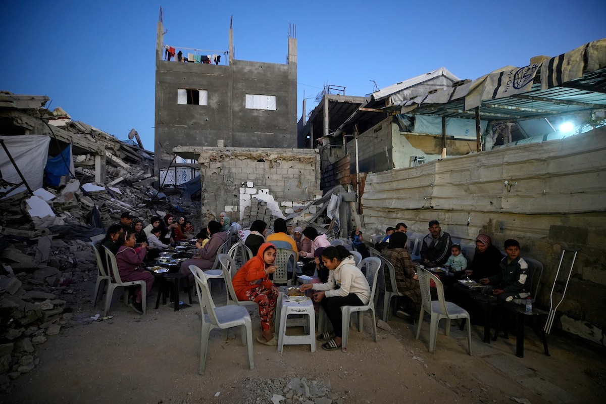 يتجمع الفلسطينيون بين المنازل المدمرة لتناول وجبة الإفطار معًا خلال شهر رمضان المبارك في شمال قطاع غزة، 22 فبراير/شباط 2026. صورة: عمر أشتوي